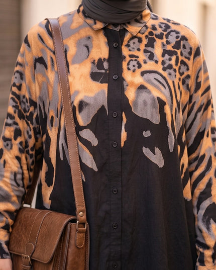 Brand Zee long sleeve button-down shirt in black, ochre, and grey animal print worn with a brown crossbody bag