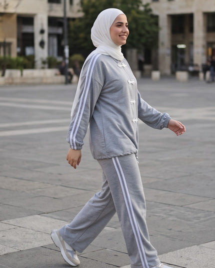 Brand Zee grey two-piece sporty lounge set with white side stripes and decorative knot fastenings worn by a woman