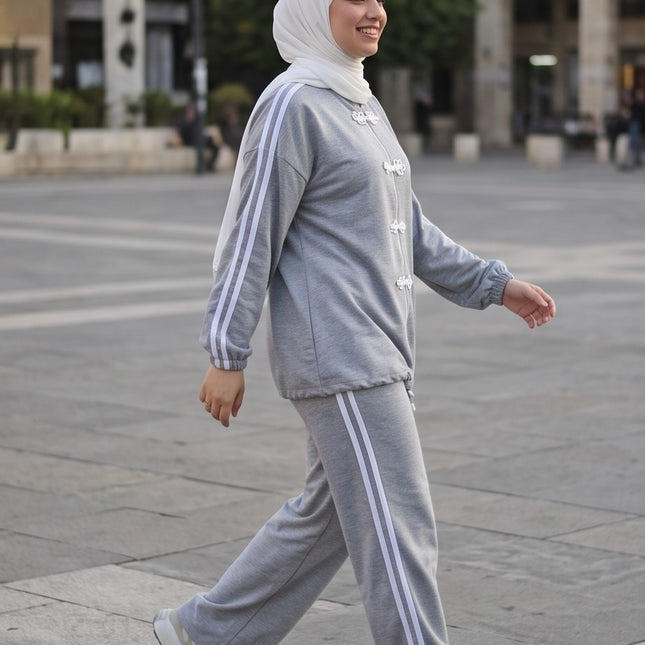 Brand Zee grey two-piece sporty lounge set with white side stripes and decorative knot fastenings worn by a woman