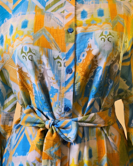 Brand Zee long sleeve shirt featuring a vibrant yellow, blue, and green abstract print with a tie-waist and buttons.