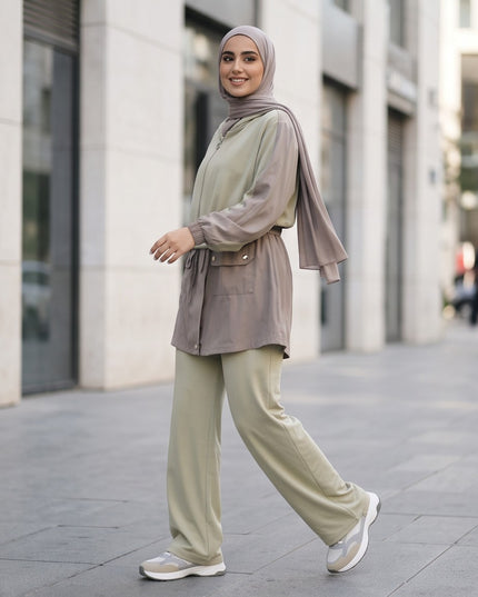 Brand Zee two-piece sage green and taupe hooded jacket and wide-leg trouser set worn by a woman in an urban setting.