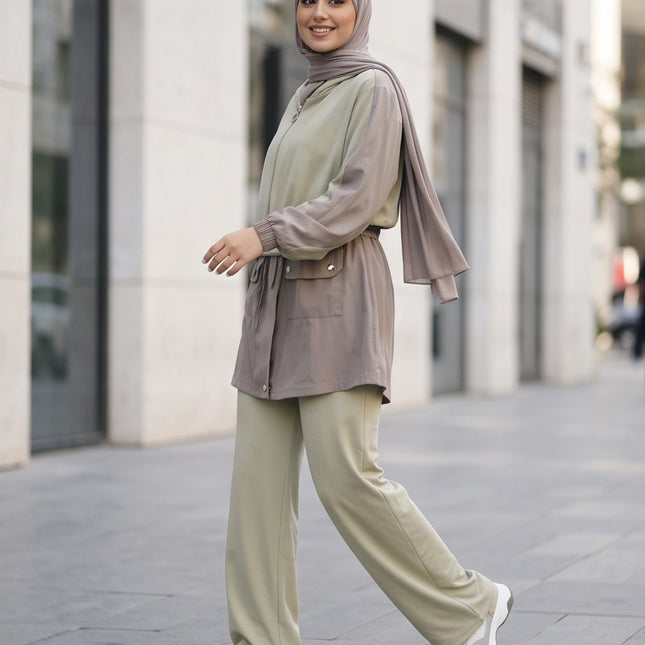 Brand Zee two-piece sage green and taupe hooded jacket and wide-leg trouser set worn by a woman in an urban setting.